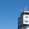 A modern air traffic control tower with antennas on top against a clear blue sky.