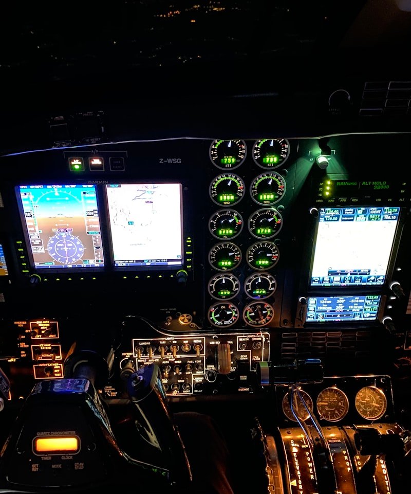 The cockpit of an aircraft at night, featuring illuminated control panels, gauges and digital screens.