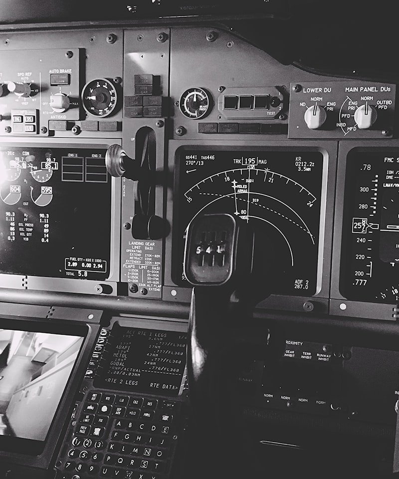 A detailed view of an aircraft cockpit with control panels, radar and navigation screens and a steering yoke.
