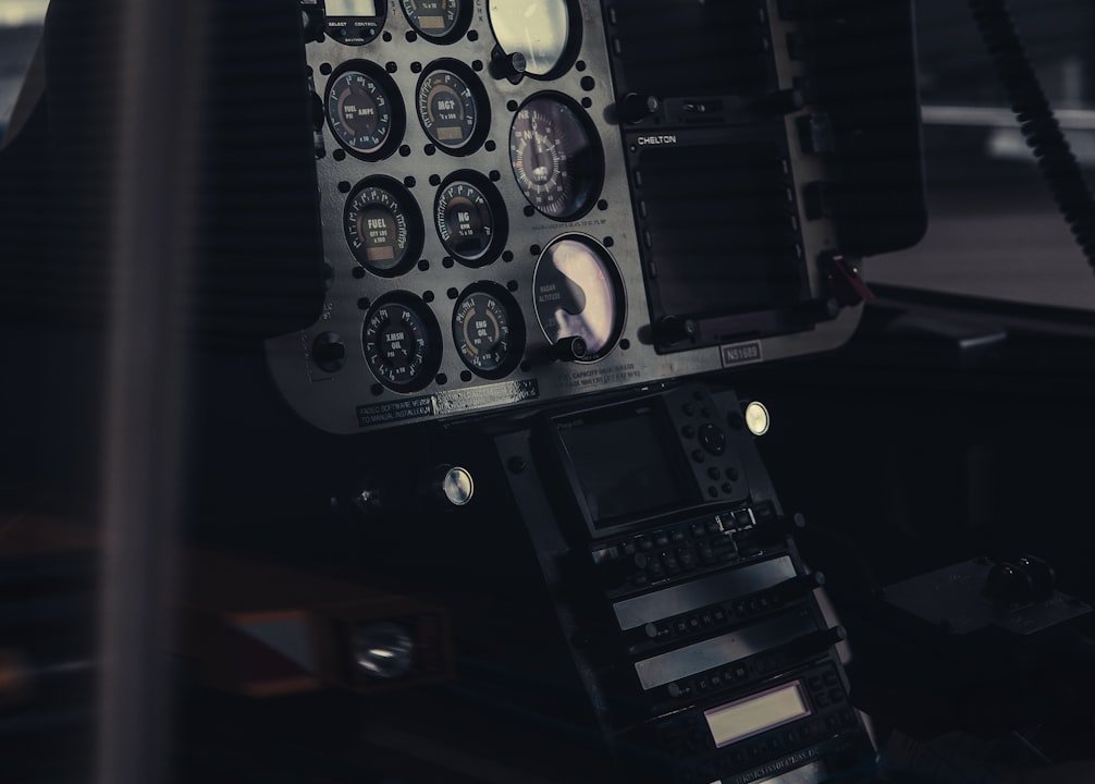 A close-up of an aircraft cockpit featuring analog dials, gauges and electronic screens in dim lighting.
