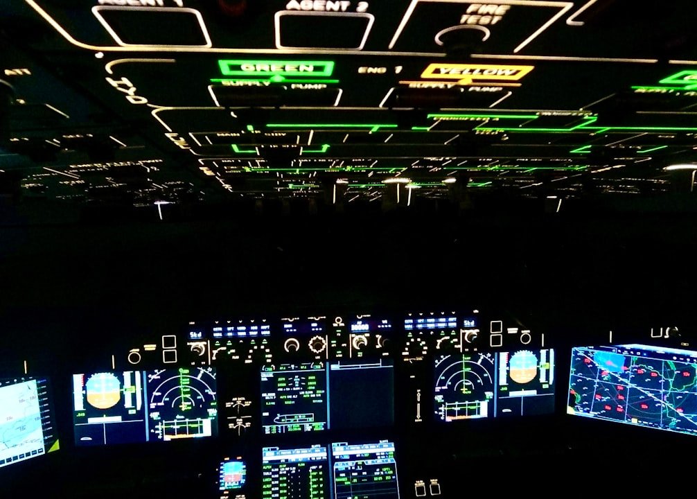 A cockpit filled with illuminated panels and displays showing complex data and indicators in a darkened environment.