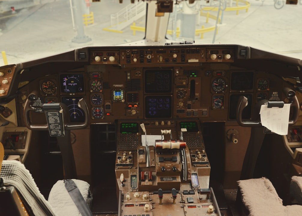 A cockpit filled with instruments, gauges and controls, with dual yokes and a view of the airport through the windows.